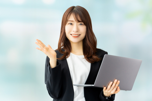 若い女性がノートパソコンを片手に説明している