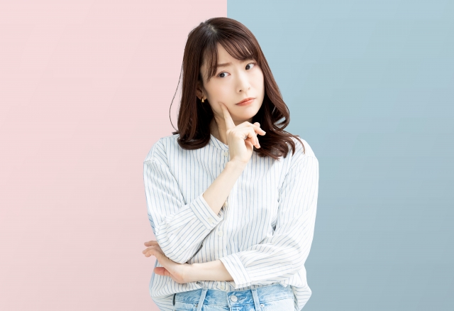 若い女性が頬に人差し指をあてて考え事をしていえる。