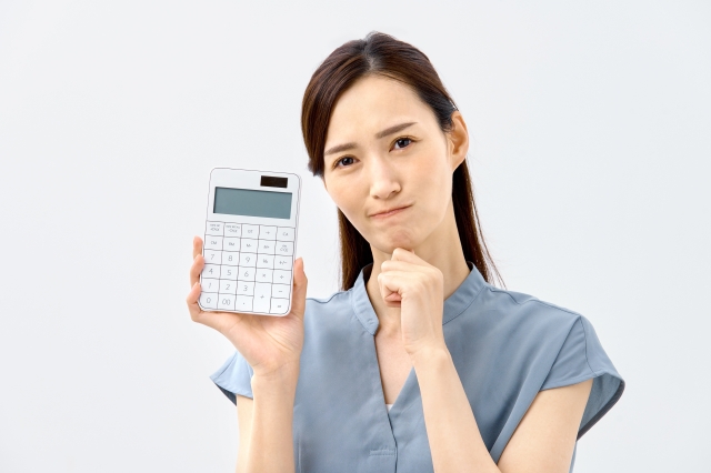 若い女性がが電卓を持って価格について悩んでいる