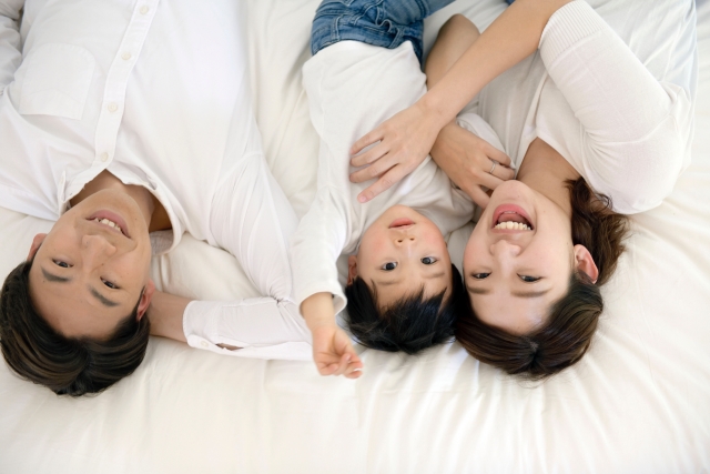 マットレスに横たわる親子3人