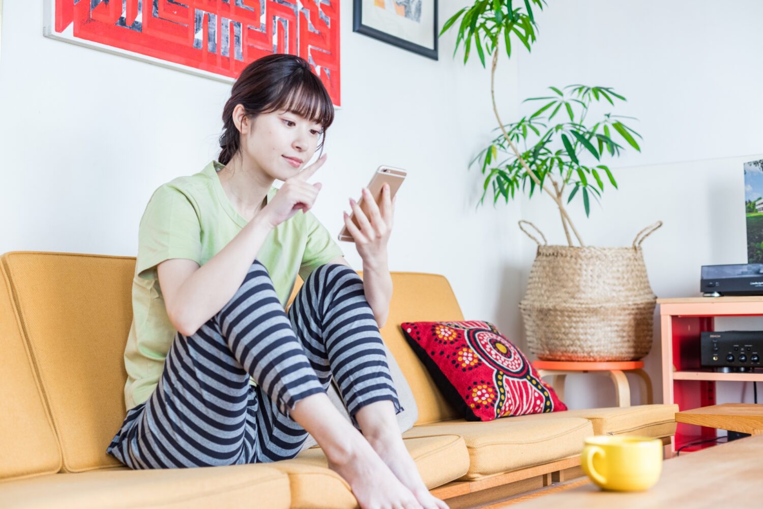 ソファに座ってスマホを見てる女性