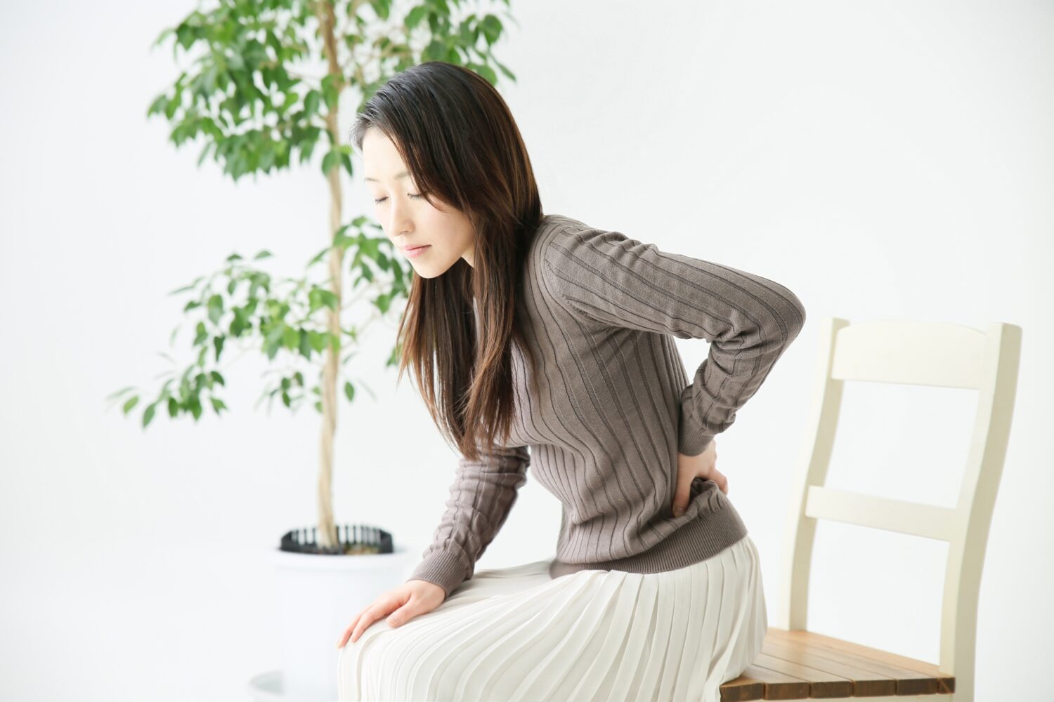 腰を手で押さえてる女性
